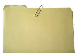 A manila file folder, paper clipped closed
